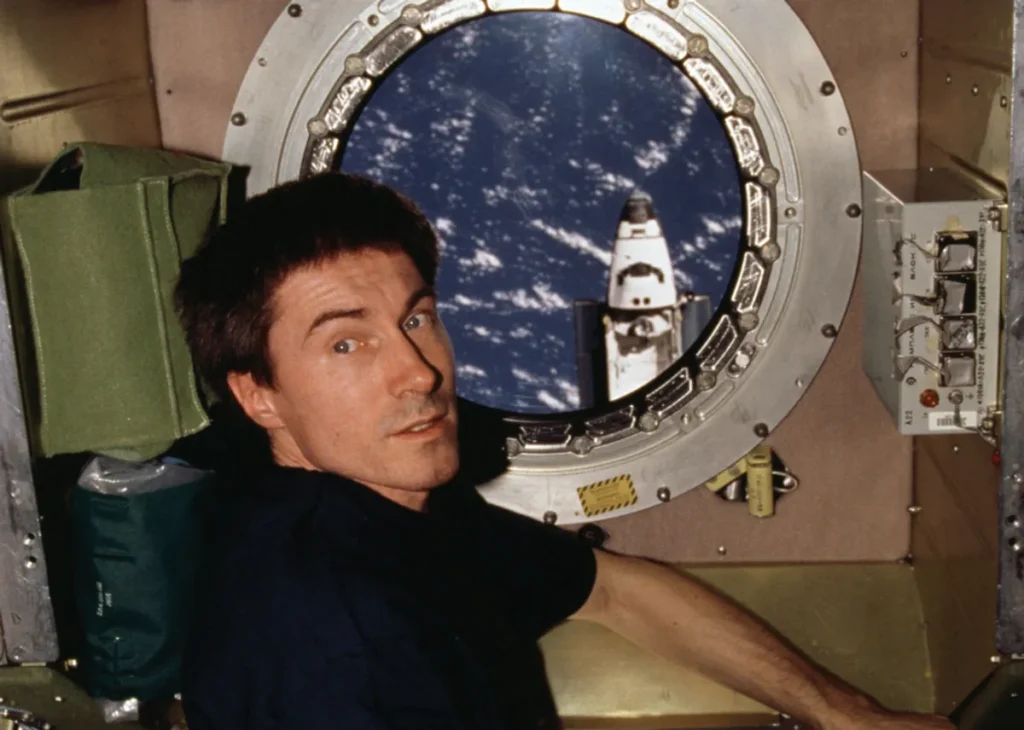 O cosmonauta Serguei Krikalev observa pela escotilha do módulo de serviço Zvezda, na Estação Espacial Internacional, enquanto o ônibus espacial Atlantis se aproxima para o acoplamento. (Créditos: NASA)